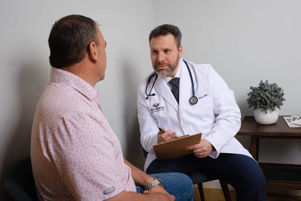 Dr Fine conferring one-on-one with a male patient in an exam room.