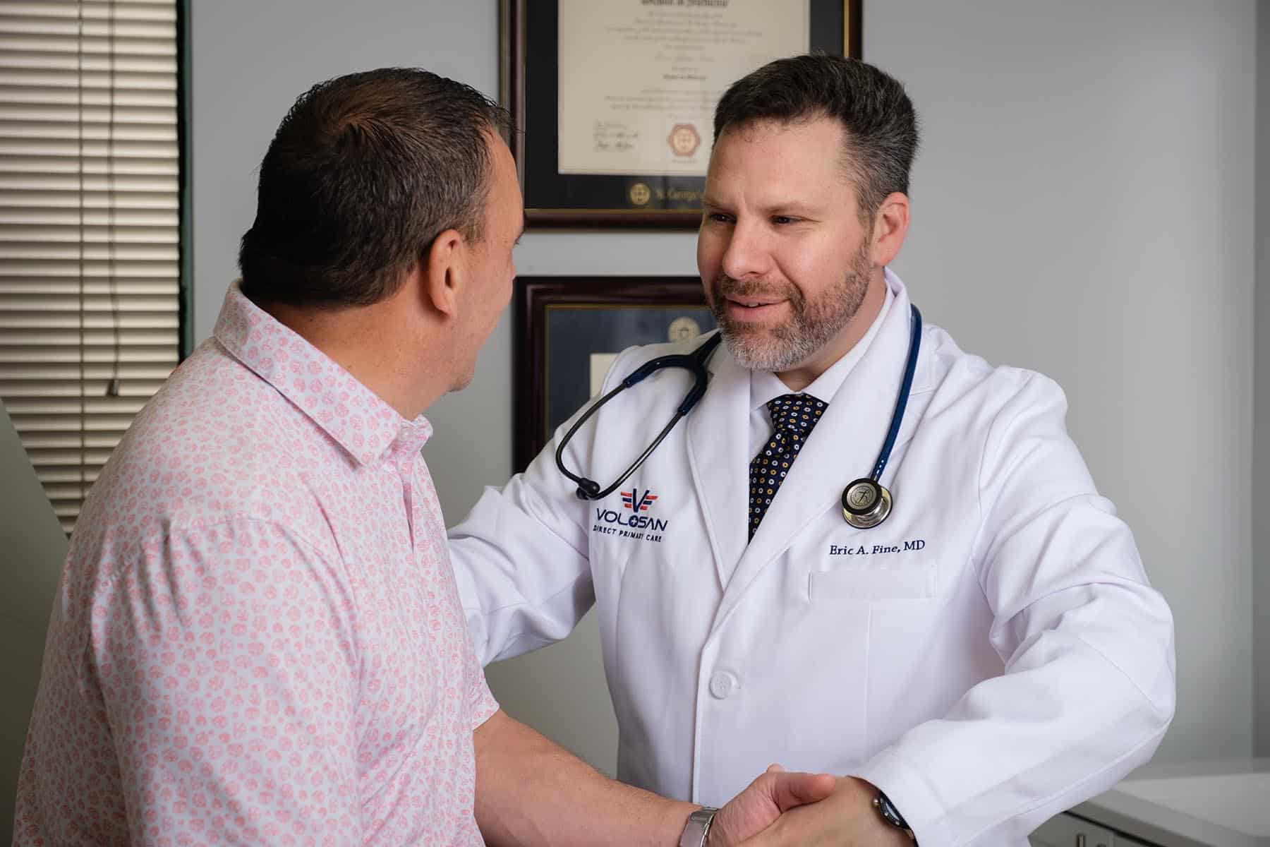 Dr Fine shaking hands with a male patient in the Volosan office.