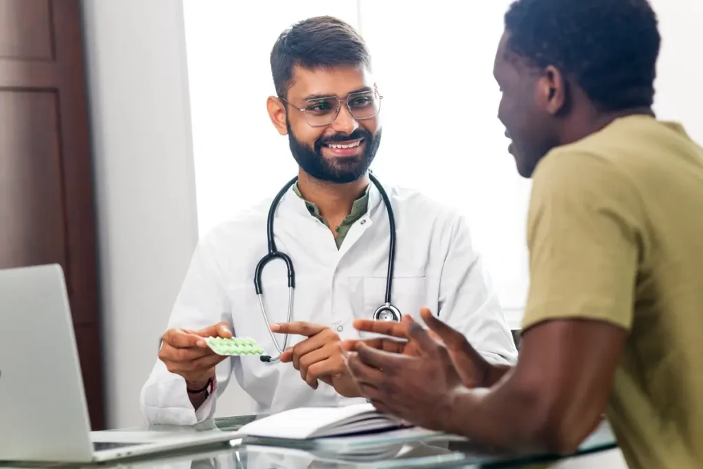 Doctor explaining a pill medications pack to a male patient in the exam room.